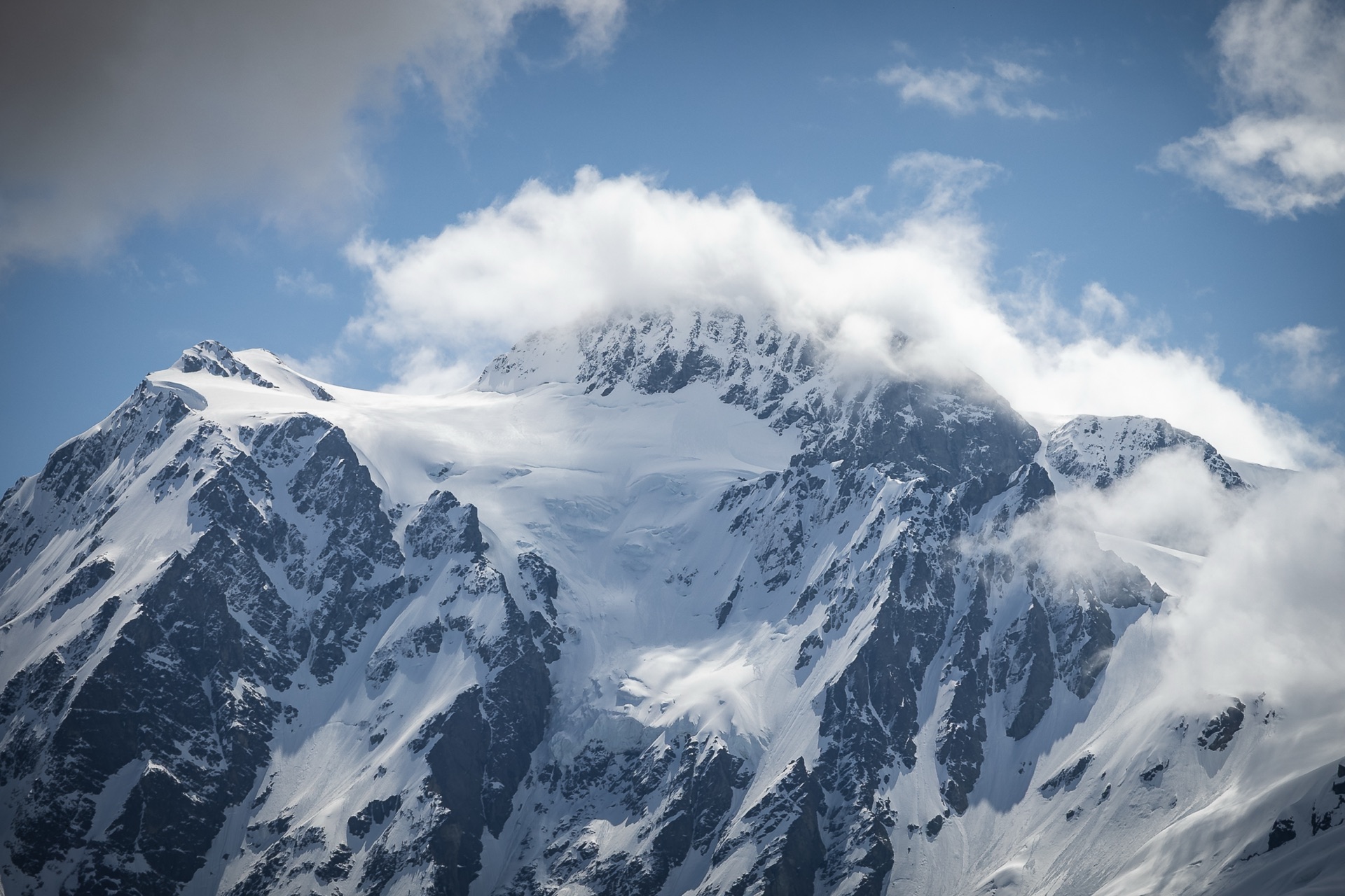 A snow-covered mountain peak wreathed in cloud